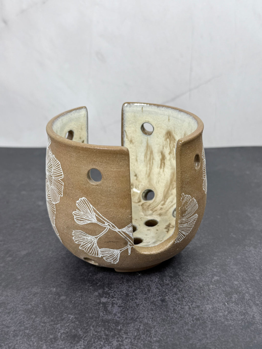 Ceramic sponge holder with floral patterns on a gray surface
